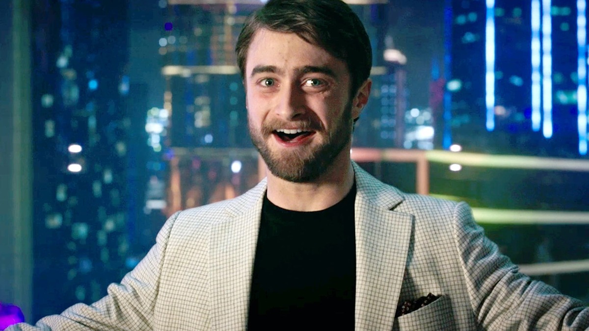 Дэниел Рэдклифф, в фильме Затерянный город, одетый в пиджак поверх футболки, небритый, но при этом улыбается